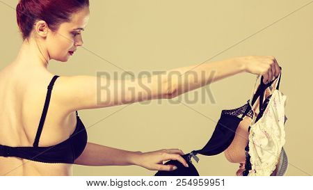 Bosom Concept. Slim Attractive Red Hair Woman Wearing Black Underwear Holding Many Bras In Hand, Cho