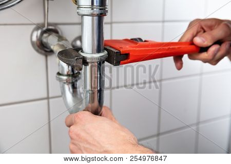 Plumber Repairing Sink With Adjustable Wrench