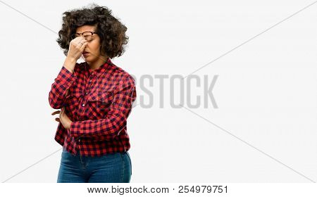 Beautiful arab woman with sleepy expression, being overworked and tired, rubbes nose because of weariness