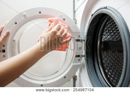 Photo of woman hands wiping orange cloth washing machine