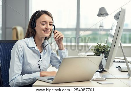Smiling Young Business Woman Using Headset For Communcation With Clients
