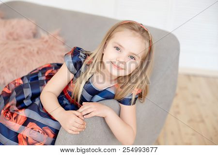 Attractive Little Girl In Colorful Dress Spinning Around Indoors
