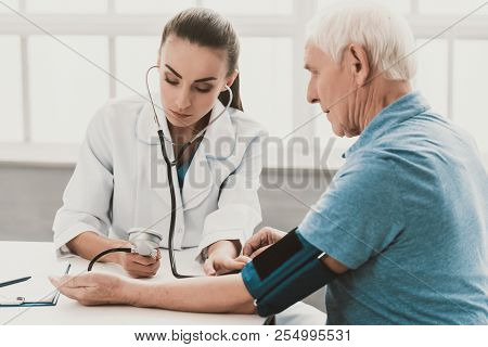 Young Female Doctor Examining Senior Patient. Young Woman Doctor Wearing White Coat Examining Senior