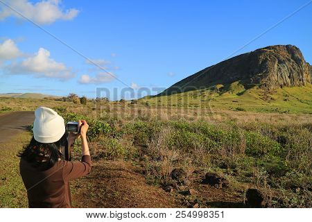 Young Female Tourist Taking Pictures Of Rano Raraku Volcano, Quarry Of Moai Statue In The Ancient Ti