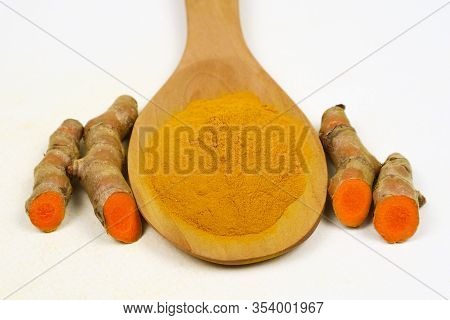 Turmeric Powder In A Wooden Spoon And Fresh Turmeric Roots Isolated On A White Background Is An Ingr