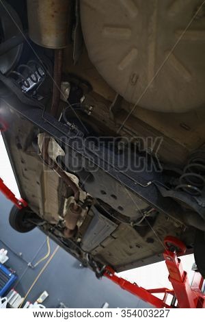 Close-up Of Automobile Lifted With Jackscrew And Inspection From Below. Car Maintenance Shop Concept