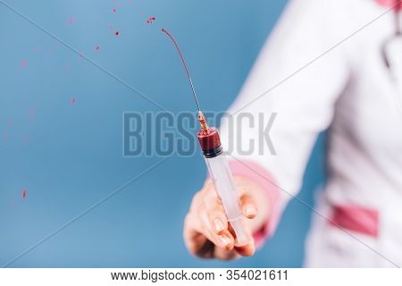 Young Girl Doctor Holding Syringe With Blood In His Hand In A White Coat And Mask On Her Face