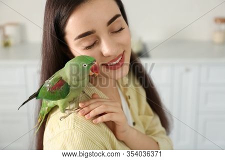 Young Woman With Alexandrine Parakeet Indoors. Cute Pet