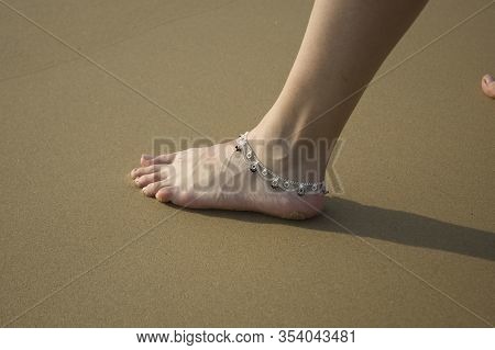 Closeup Of A Womans Legs With An Anklet Jewelry On The Beach