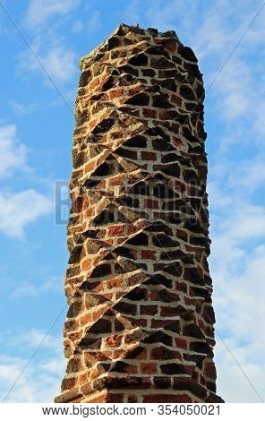 Tudor Barley Sugar Twist Red Brick Chimney Pot With A Blue Sky With White Cloud Background.