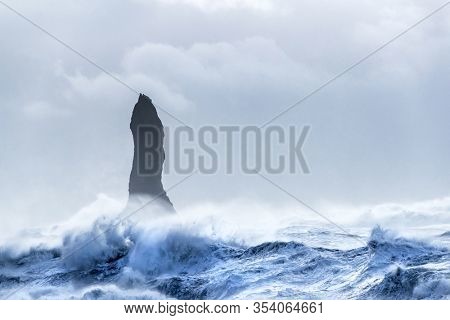 Reynisdrangar basalt rock column standing in a stormy sea of the coast of Iceland. The formations here are also known as the Troll toes, due to Icelandic myth. 