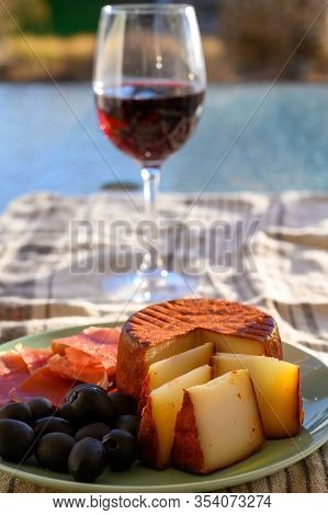 Tastes Of Spain, Jamon Iberian, Black Olives, Manchego Cheese With Red Paprika And Glass With Red Ri