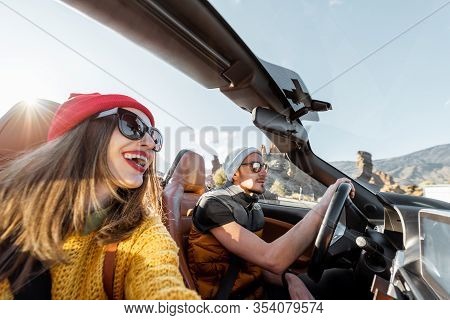 Selfie Portrait Of A Happy Couple While Driving Convertible Sports Car On The Desert Road During A S