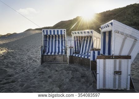 Beach Chairs At Sunrise On Sylt Island, Germany. Wicker Chairs On An Empty Beach At The North Sea An