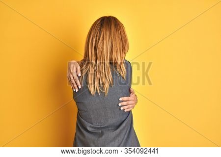 Redhead caucasian business woman over yellow isolated background Hugging oneself happy and positive from backwards. Self love and self care