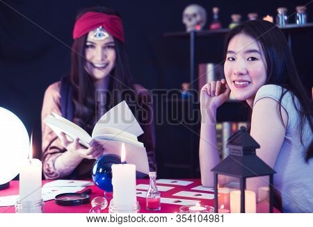 A Beautiful Asian Woman Is Performing A Ritual For Fortune Telling With The Fortune Teller, A Woman 