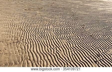 Patterns Left By The Retreating Tide In The Sand On A Beach