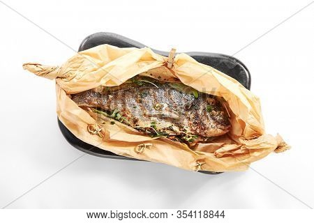 Baked dorado fish in parchment. Grilled tuna in black plate. Cooked dolphinfish with herbs. Served seafood restaurant food. Marine delicacy, mediterranean delicious gourmet meal
