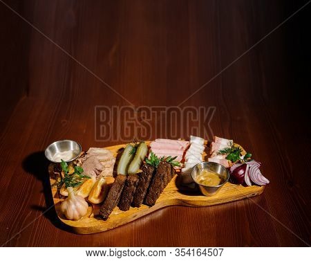 Sliced From Various Types Of Lard, Ham With Sauce And Pickles On A Wooden Board.