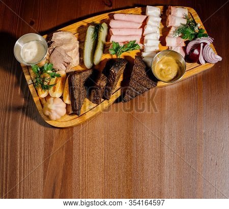 Sliced From Various Types Of Lard, Ham With Sauce And Pickles On A Wooden Board. Top View