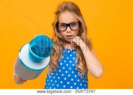 Portrait Of Young Caucaian Girl With Long Fair Hair In Black Glasses With A Microphone Interwiews An