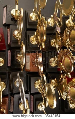 Group of golden trophy over blackboard background. top view. flat lay.Trophy is a specific achievement, serves as recognition / evidence of merit, awarded for sporting events