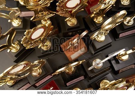 Group of golden trophy over blackboard background. top view. flat lay.Trophy is a specific achievement, serves as recognition / evidence of merit, awarded for sporting events