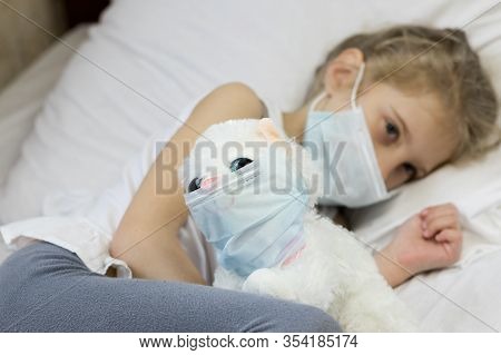 A Girl With White Hair In A Medical Mask On Her Face. Nearby, A Soft Toy On Her Face Is Also A Cough