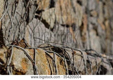 Gabion. Stone Fence In A Metal Mesh. Crushed Stone Packed In Wire Mesh. Granite Texture. Selective F