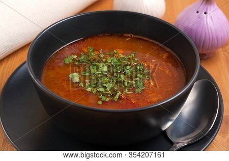 Kharcho Soup With Beef In A Dark Bowl Decorated With Greens