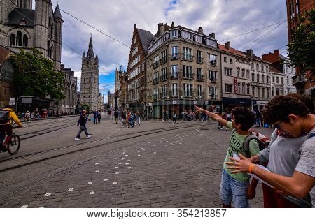 Ghent, Belgium, August 2019. Two Boys With Their Mother Consult The Tourist Map, Behind Them Are The