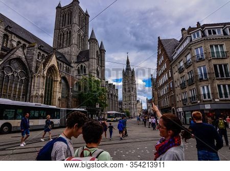 Ghent, Belgium, August 2019. Two Boys With Their Mother Consult The Tourist Map, Behind Them Are The