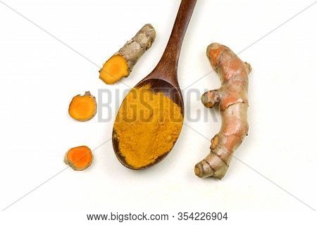 Turmeric Powder In A Wooden Spoon And Fresh Turmeric Roots Isolated On A White Background Is An Ingr