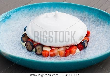 Anna Pavlova Dessert With Berries In A Blue Plate