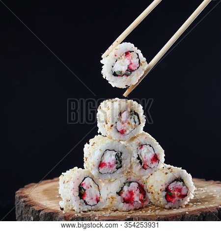 Rolls Lined With A Pyramid, Non-standard Flow On A Piece Of Wood On A Black Background. The Concept 