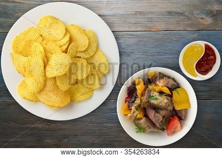Potato Chips On A White Plate With Vegetarion Salad. Chips On A Blue Wooden Background Top View.