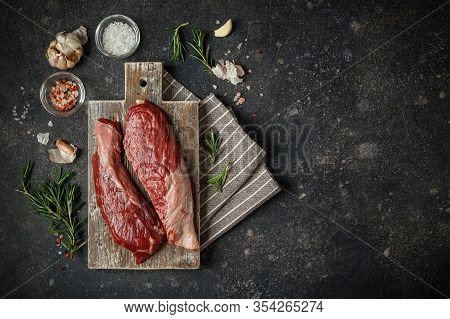 Raw Fresh Steak Sirloin Flap Served With Rosemary, Garlic And On Wooden Cutting Board. Black Angus B