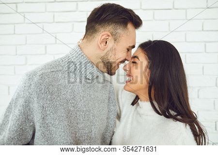 Young Smiling Couple Smiling On A White Brick Background