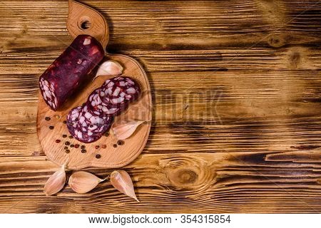 Cutting Board With Sliced Salami Sausage On Rustic Wooden Table. Top View