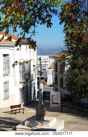 Estepa, Spain - November 13, 2008 - Metal Cross On A Stone Pillar Surrounded By Townhouses In The Pl