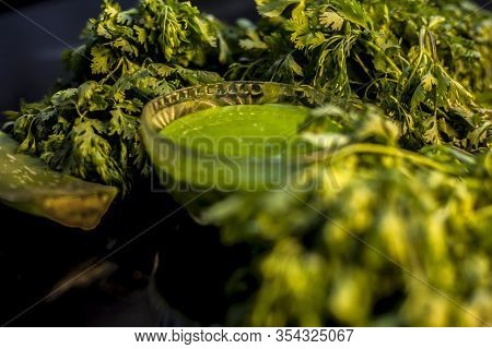 Anti-aging Face Mask On The Black Colored Glossy Surface Consisting Of Fresh Green Cilantro Leaves,