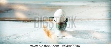 Pastel Colored Easter Egg In A Egg Cup With A Chicken Feather On Old Gray Vintage Wood. Horizontal A