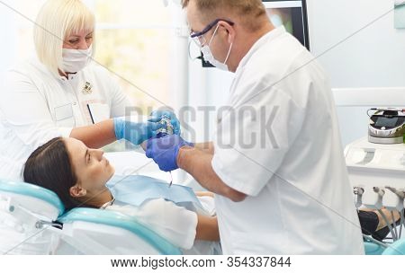 Doctor Dentist Treats Teeth Of A Beautiful Young Girl Patient. The Girl On Reception At The Dentist.