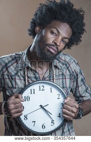 Afroamerikaner In A Checkered Shirt Holds The Large White Clock