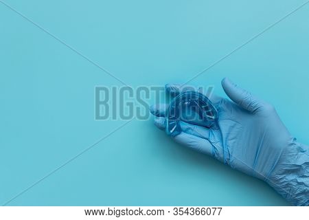 Hand Of Medic Wearing Blue Latex Glove Holding Myofunctional Trainer On Blue Background. Teeth Corre