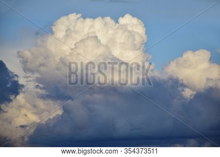 Puffy Clouds Blue Sky. Dark Clouds Lit By The Evening Sun With Gleams Of Blue Sky.