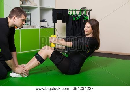 A Young Woman With A Personal Trainer Doing Fitness Exercises In An Ems Suit. Concept: Health, Ems T