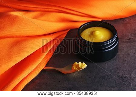 Beautiful Picture Of Golden Solid Skincare Oil In Elegant Black Glass Jar And Golden Spoon Accentuat