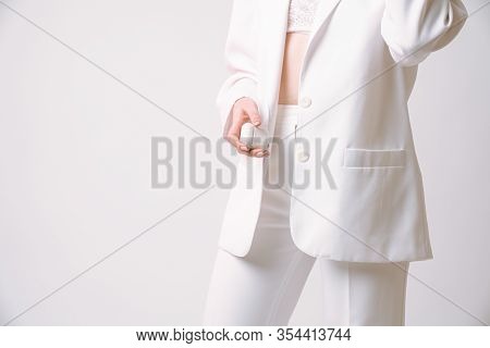 Cropped Photo Of A Gorgeous Female In White Suit Who Holds Wireless Headphones In Her Hand, Isolated
