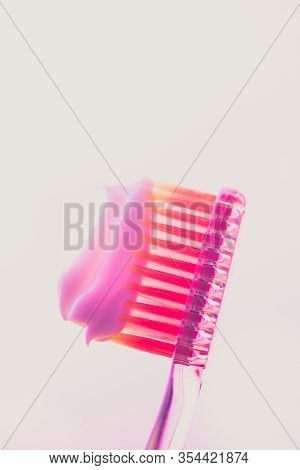 Pink Plastic Toothbrush With A White Toothpaste On An Isolated Background.